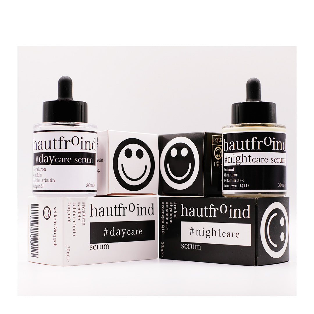 Hautfroind Daycare & Nightcare Seren – feuchtigkeitsspendende Hautpflege und Gesichtspflege für Tag & Nacht. Mit Hyaluronsäure, Retinol & Coenzym Q10 für Hydratation, Schutz & Regeneration. Fördert die Kollagenproduktion & sorgt für strahlende, glatte & gesunde Haut rund um die Uhr. Die Flaschen Hautfroind Daycare Serum steht neben der Flasche Hautfroind NIghtcare Serum. Frontal fotografiert vor hellem Hintergrund. Die Verpackung stehen daneben. Die Oberseite der Verpackungen zeigt Smileys.