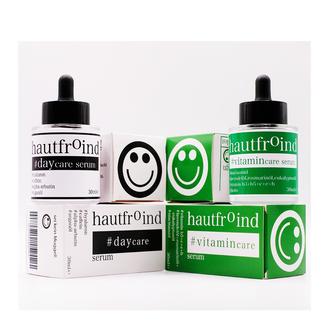 Hautfroind Daycare & Vitamincare Seren – feuchtigkeitsspendende Hautpflege und Gesichtspflege mit Hyaluronsäure, Vitamin C & Niacinamid. Spendet Feuchtigkeit, fördert die Kollagenproduktion & schützt vor freien Radikalen. Für eine strahlende, gesunde & perfekt gepflegte Haut. Hautfroind Daycare Serum und Hautfroind Vitmaincare Serum frontal abfotografiert. Neben den Verapckungen, die Oberseite der Verpackungen zeigen Smileys.