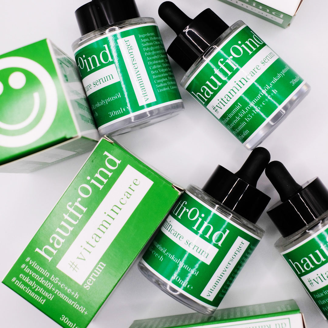 Hautfroind Vitamincare Serum – vitaminreiche Hautpflege und Gesichtspflege mit Niacinamid, Vitamin C & E. Hellt dunkle Flecken auf, fördert die Kollagenproduktion & schützt vor freien Radikalen. Feuchtigkeitsspendende Formel mit Aloe Vera & Hyaluronsäure für strahlende, gesunde Haut. Es sind die Flaschen von Vitamincare Serum von Hautfroind zu sehen. und die Verpackungen. Wild und künstlerisch angeordnet. 
