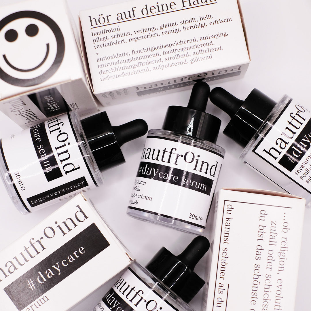 Hautfroind Daycare Serum – feuchtigkeitsspendende Hautpflege für das Gesicht mit Hyaluronsäure, Arganöl & Rosa Damascena Blütenwasser. Stärkt die Hautbarriere, verfeinert den Teint & sorgt für langanhaltende Feuchtigkeit. Leichte, schnell einziehende Gesichtspflege für strahlende Haut. Auf dem Foto sind die Flaschen des Daycare Serum zu sehen. Mit Verpackungen. Ein wenig wild angeordnet.