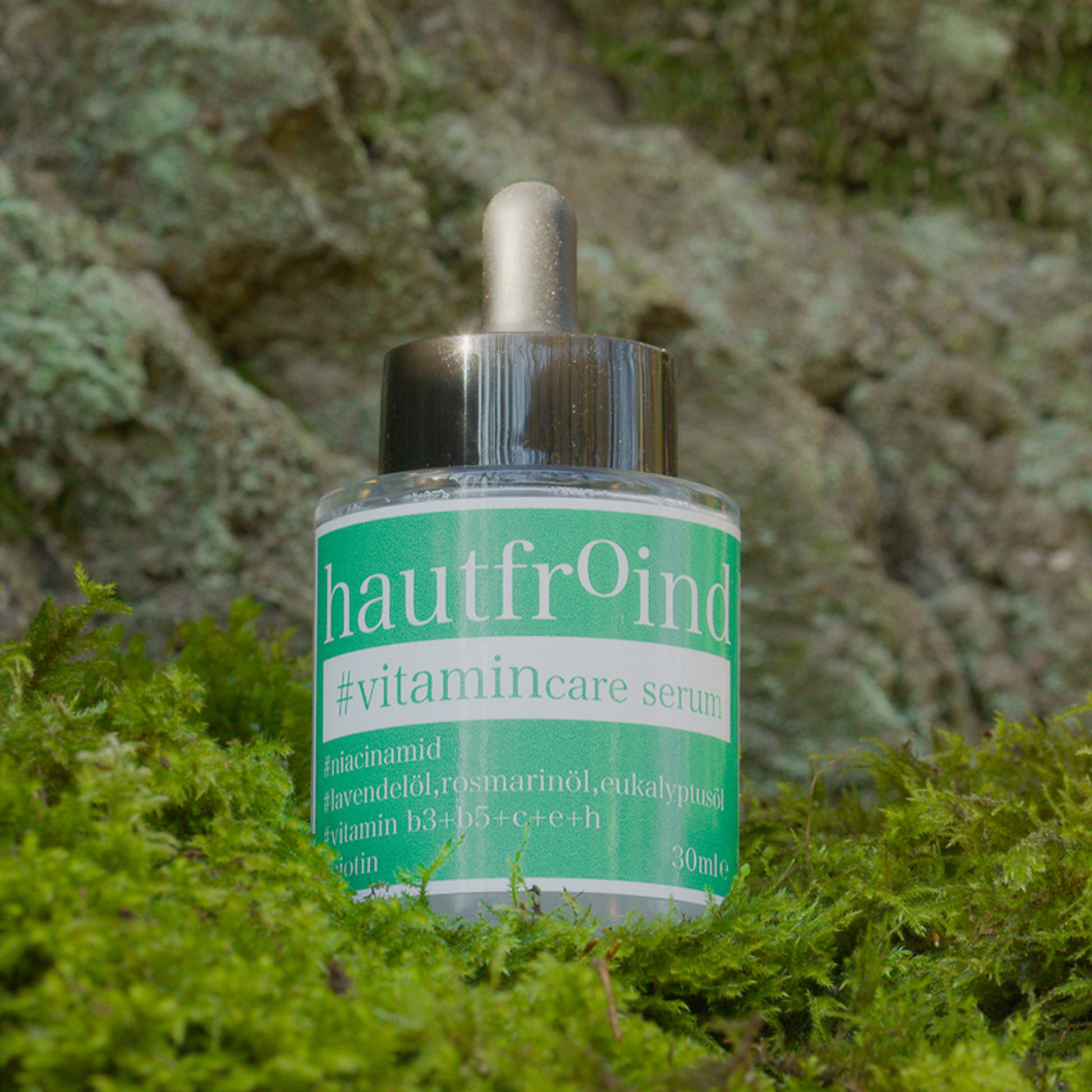 Hautfroind Vitamincare Serum – vitaminreiche Hautpflege und Gesichtspflege mit Niacinamid, Vitamin C & E. Hellt dunkle Flecken auf, fördert die Kollagenproduktion & schützt vor freien Radikalen. Feuchtigkeitsspendende Formel mit Aloe Vera & Hyaluronsäure für strahlende, gesunde Haut. Das Hautfroind Vitamincare Serum ist vor einer Felswand und auf frischem Moss zu sehen.