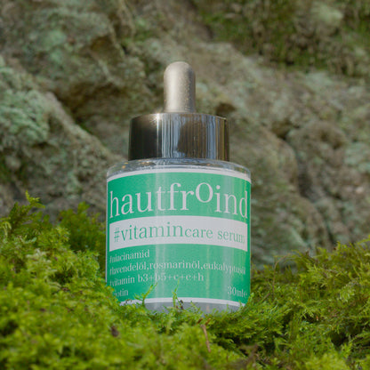 Hautfroind Vitamincare Serum – vitaminreiche Hautpflege und Gesichtspflege mit Niacinamid, Vitamin C & E. Hellt dunkle Flecken auf, fördert die Kollagenproduktion & schützt vor freien Radikalen. Feuchtigkeitsspendende Formel mit Aloe Vera & Hyaluronsäure für strahlende, gesunde Haut. Das Hautfroind Vitamincare Serum ist vor einer Felswand und auf frischem Moss zu sehen.