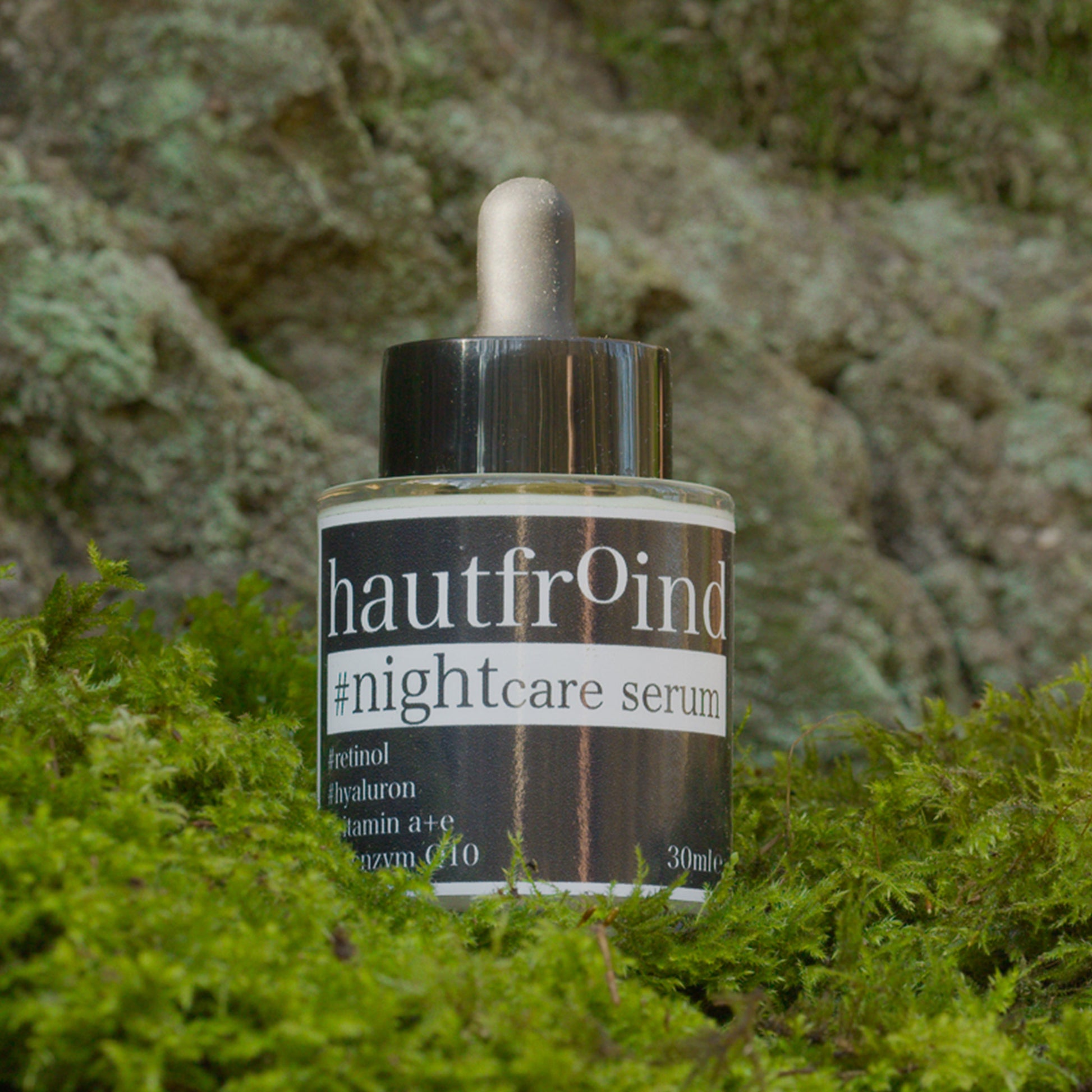 Hautfroind Nightcare Serum – regenerierende Hautpflege und Gesichtspflege mit Retinol, Coenzym Q10 & Hyaluronsäure. Fördert die Zellregeneration, stärkt die Kollagenproduktion & spendet Feuchtigkeit. Nährende Nachtpflege für glatte, erholte & strahlende Haut am Morgen. Auf dem Foto ist das Serum Nightcare vor einer Felswand und auf grünem Moss zu sehen. 