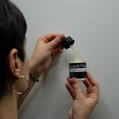 Hautfroind Nightcare Serum – regenerierende Hautpflege und Gesichtspflege mit Retinol, Coenzym Q10 & Hyaluronsäure. Fördert die Zellregeneration, stärkt die Kollagenproduktion & spendet Feuchtigkeit. Nährende Nachtpflege für glatte, erholte & strahlende Haut am Morgen. Es ist der Hinterkopf unseres Models zu sehen wie sie von der Pipette einen Tropfen in die Hautfroind nightcare Serum Flasche tropfen lässt. 