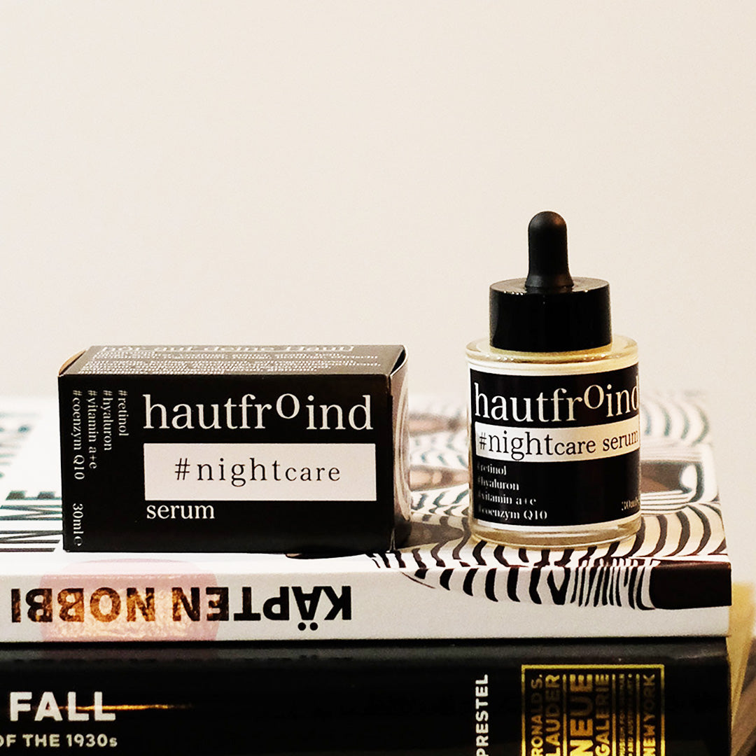 Hautfroind Nightcare Serum – regenerierende Hautpflege und Gesichtspflege mit Retinol, Coenzym Q10 & Hyaluronsäure. Fördert die Zellregeneration, stärkt die Kollagenproduktion & spendet Feuchtigkeit. Nährende Nachtpflege für glatte, erholte & strahlende Haut am Morgen. Das Hautfroind NIghtcaer Serum steht mit der Verpackung und dem Fläschchen auf einem kleinen Bücherstapel.