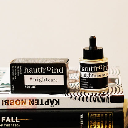 Hautfroind Nightcare Serum – regenerierende Hautpflege und Gesichtspflege mit Retinol, Coenzym Q10 & Hyaluronsäure. Fördert die Zellregeneration, stärkt die Kollagenproduktion & spendet Feuchtigkeit. Nährende Nachtpflege für glatte, erholte & strahlende Haut am Morgen. Das Hautfroind NIghtcaer Serum steht mit der Verpackung und dem Fläschchen auf einem kleinen Bücherstapel.